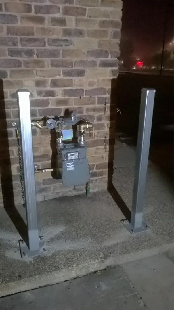 New gas meter installation between steel posts at a brick building