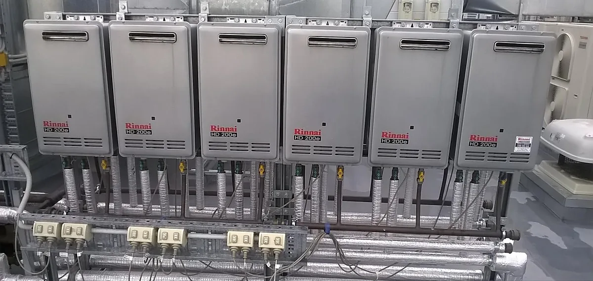 Six Rinnai HD200e heaters in a row on a commercial plant rack with insulated pipework below