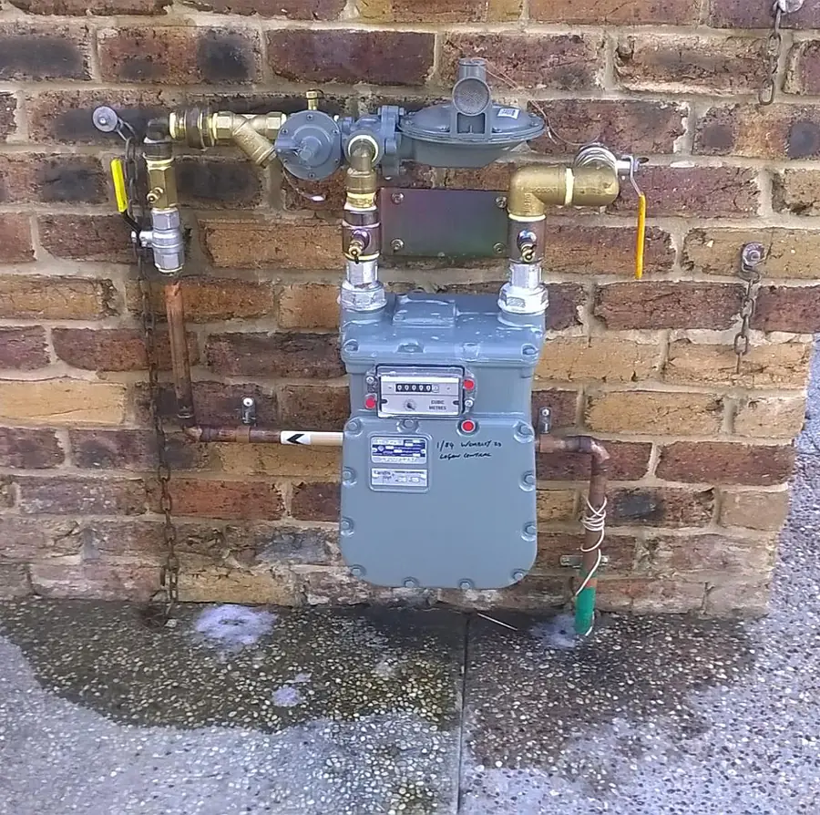 Natural gas meter and regulator with new brass fittings and pipework on a brick wall